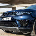 Close-up of a blue Range Rover Sport showcasing its sleek front design, featuring a bold grille and an elegant license plate.