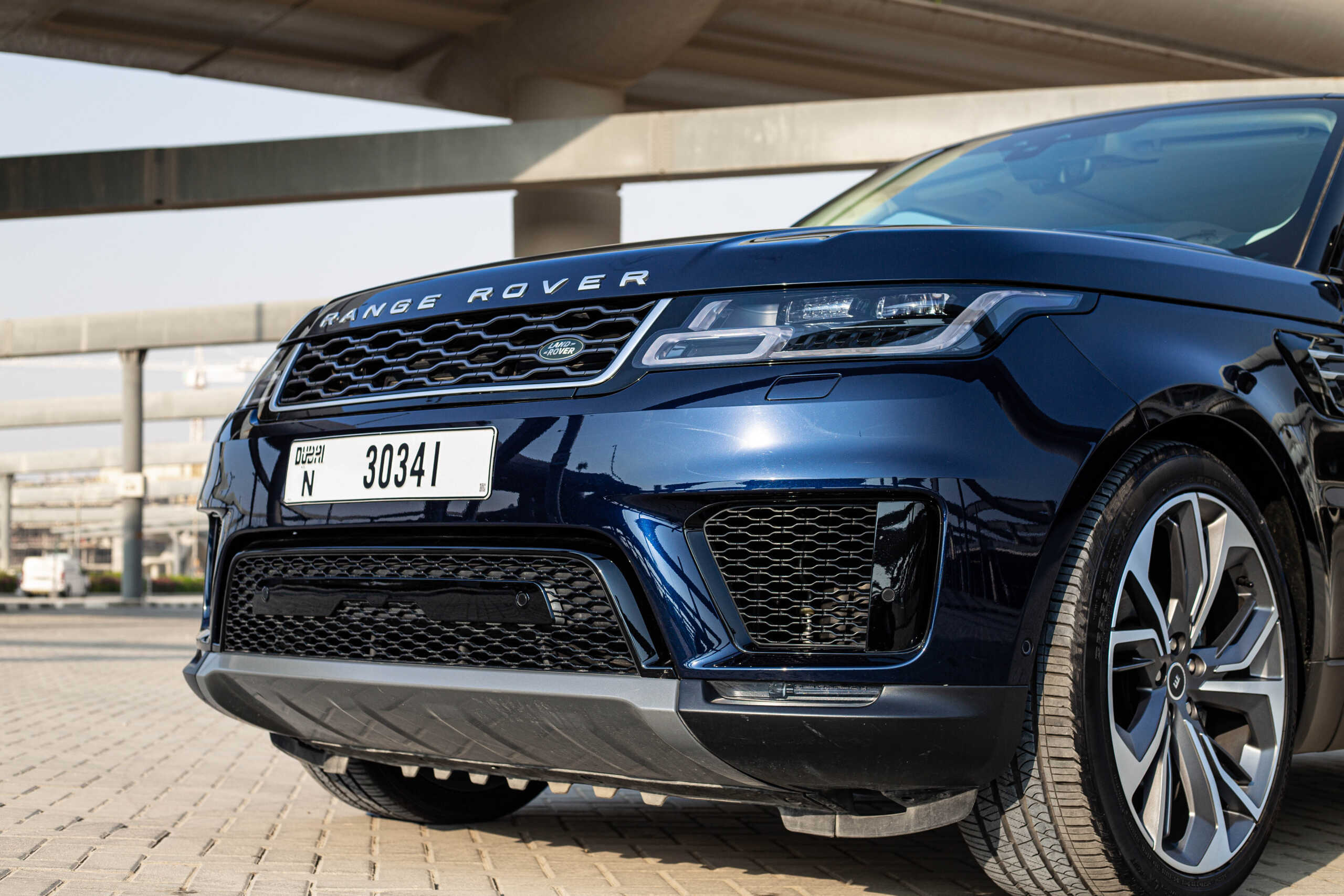 Close-up of a blue Range Rover Sport showcasing its sleek front design, featuring a bold grille and an elegant license plate.
