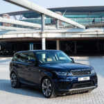 A sleek black Range Rover parked on a paved area with modern architecture in the background, showcasing luxury and style.